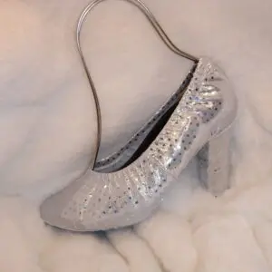 A silver color heel sandle on a white sheet