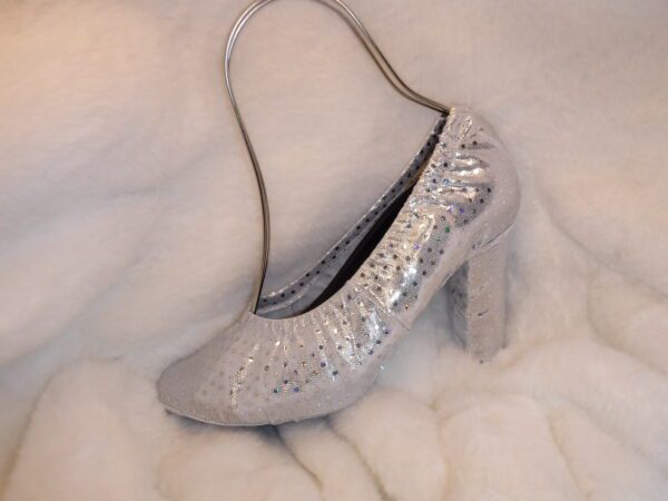 A silver color heel sandle on a white sheet